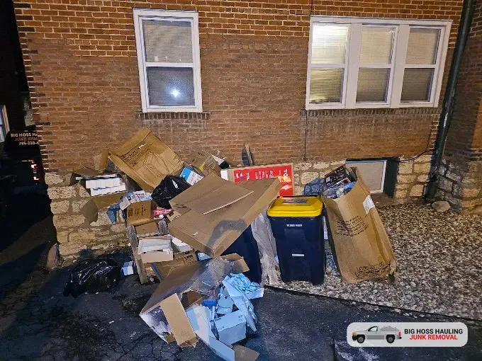 A pile of boxes and trash outside an apartment building