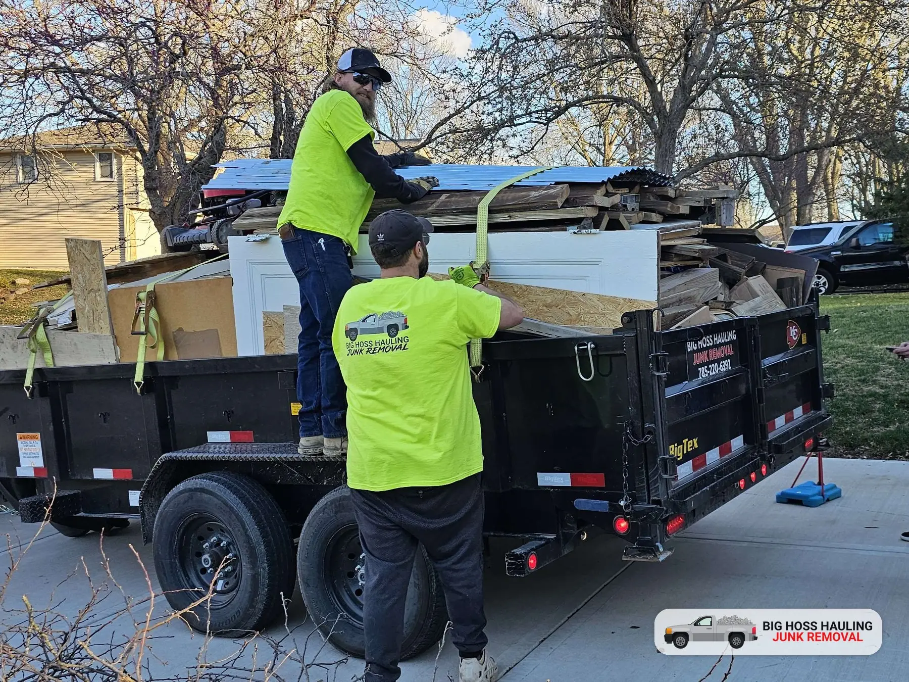 Big Hoss Hauling crew loading a full dump trailer in a driveway