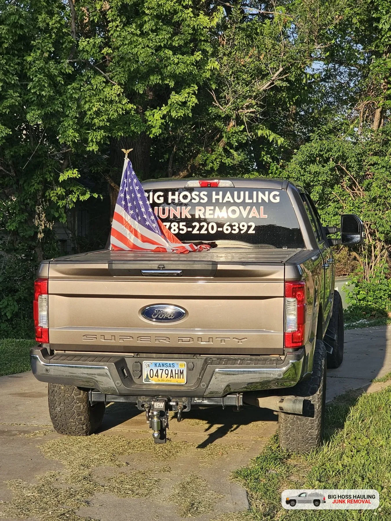 Big Hoss Hauling truck with an American flag and the company phone number on the window