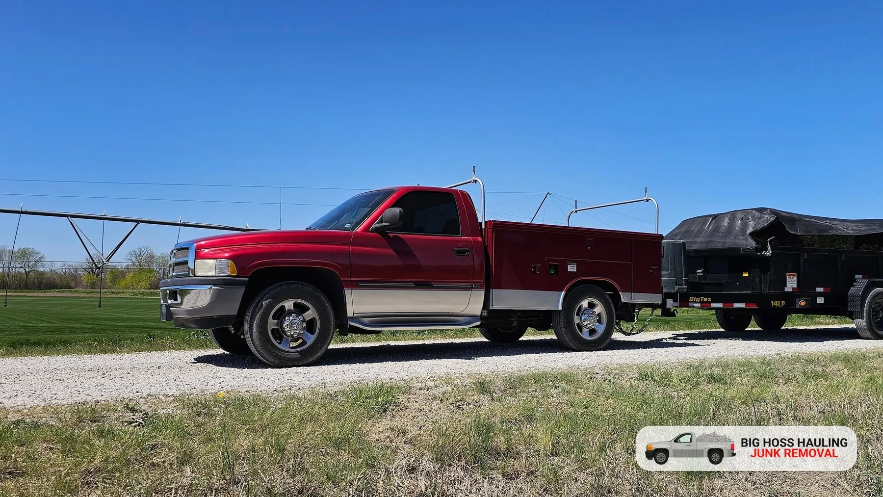 Big Hoss Hauling red pickup towing a black dump trailer on a sunny day