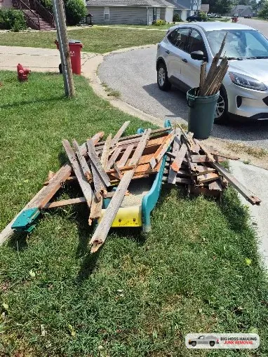 A pile of old wood waiting for pickup on a lawn